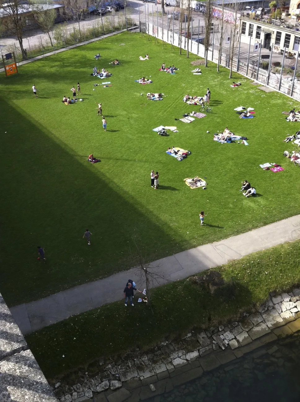 People sunbathing on the grass lawn of the Marzili beside the Aare in Bern
