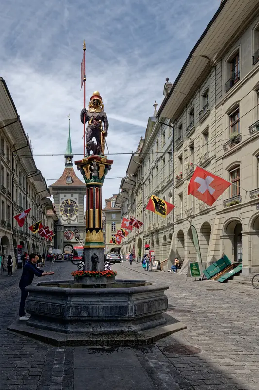 The Zähringerbrunnen on Kramgasse — a bear in armour atop a painted column, with the Zytglogge clock tower behind